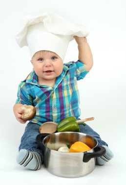 şef şapkasını pan ve sebzeler üzerinde beyaz izole, küçük çocuk