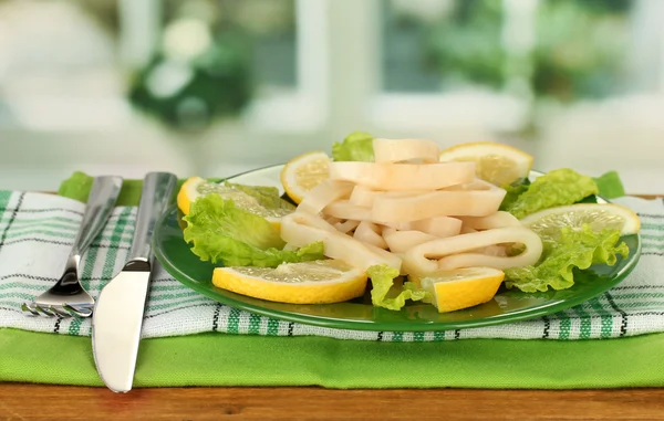 Cooked squid rings on lettuce with lemon on the plate close-up — Stock Photo, Image