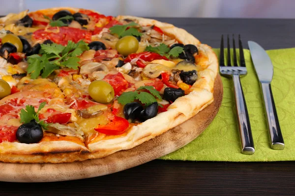 Pyszną pizzę z bliska na drewnianym stole na tle pokój — Zdjęcie stockowe