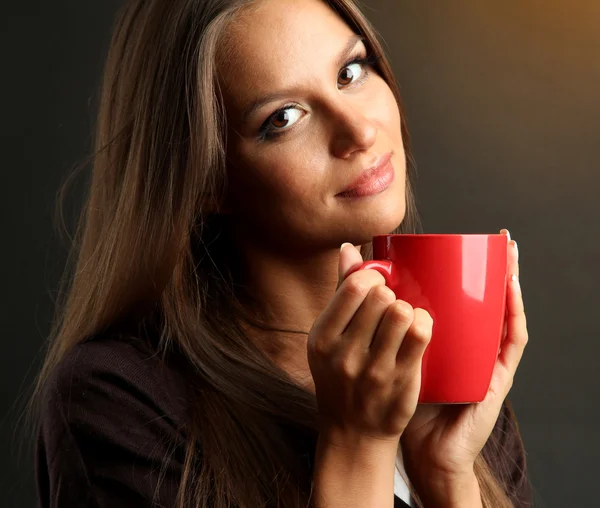 Schöne junge Frau mit Tasse Kaffee, auf braunem Hintergrund — Stockfoto