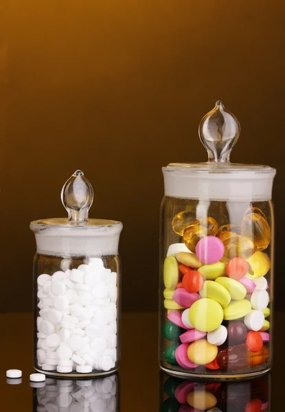 Capsules and pills in receptacles on orange background — Stock Photo, Image