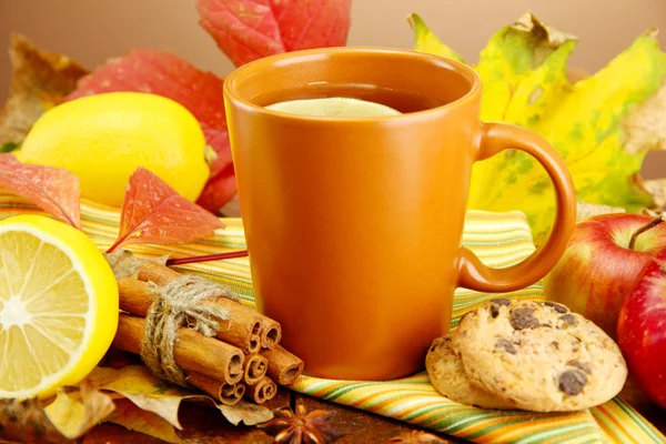 Cup of hot tea and autumn leaves, on brown background — Stock Photo, Image