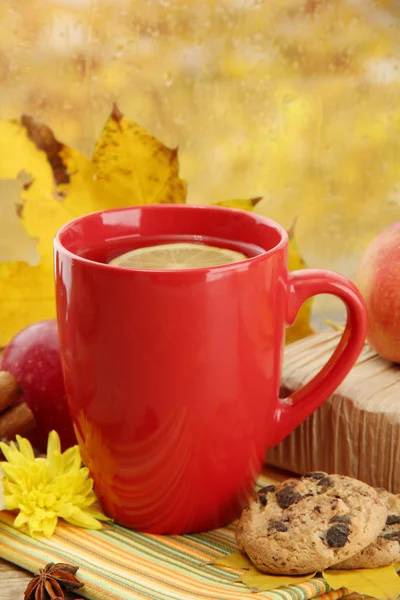 Beker van hete thee en herfst bladeren, op regen achtergrond — Stockfoto