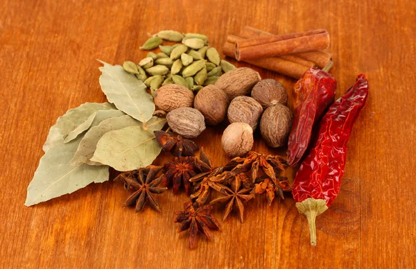 Nootmuskaat en andere specerijen op houten achtergrond — Stockfoto