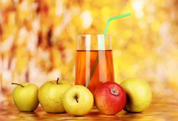Nützlicher Apfelsaft mit Äpfeln auf herbstlichem Hintergrund — Stockfoto