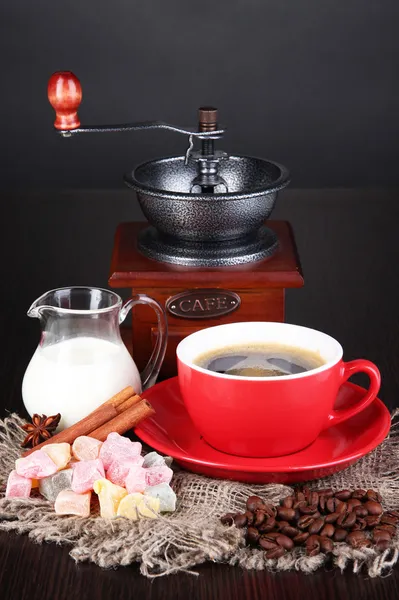 Tasse rouge de café avec rahat délice, lait et moulin à café sur table en bois — Photo