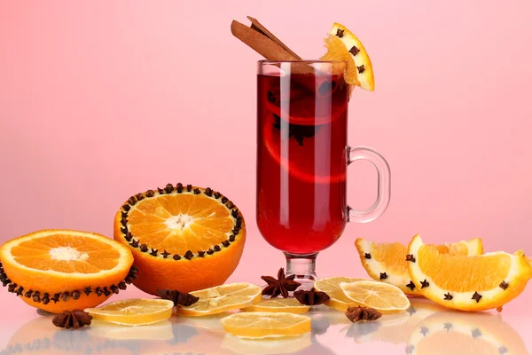 Fragrant mulled wine in glass with spices and oranges around on red background — Stock Photo, Image