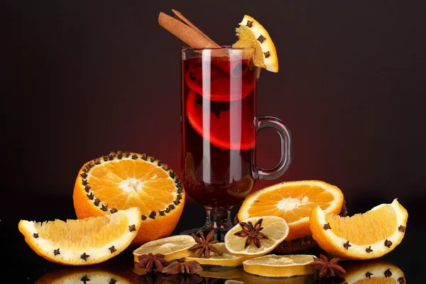 Vino caliente fragante en vaso con especias y naranjas sobre fondo rojo — Foto de Stock