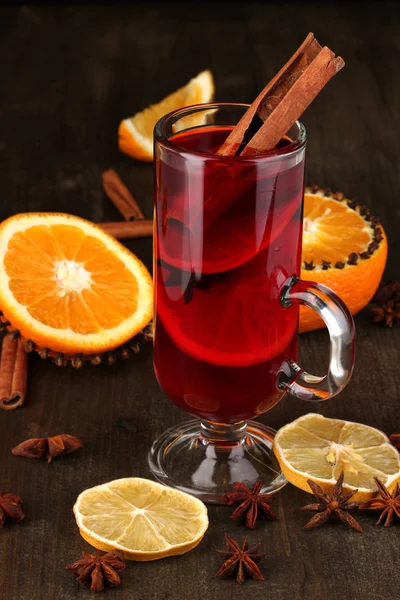 Αρωματικά mulled κρασί σε ποτήρι με μπαχαρικά και τα πορτοκάλια γύρω στο ξύλινο τραπέζι — Φωτογραφία Αρχείου