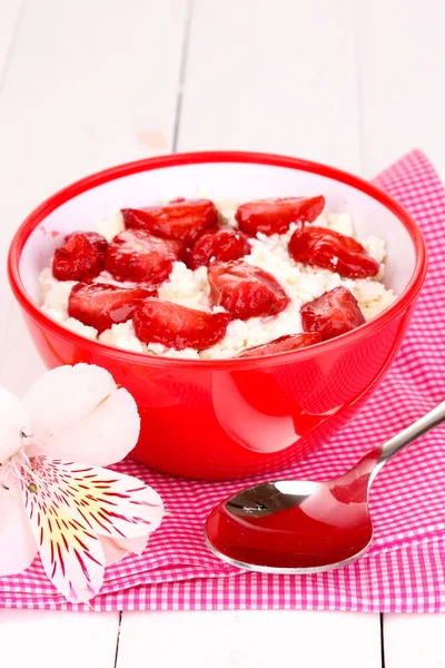 Τυρί cottage σε κόκκινο μπολ με φέτες τις φράουλες στο λευκό ξύλινο τραπέζι — Φωτογραφία Αρχείου