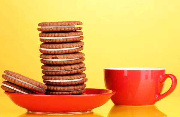 Chocolate cookies with creamy layer on red plate yellow background — Stock Photo, Image