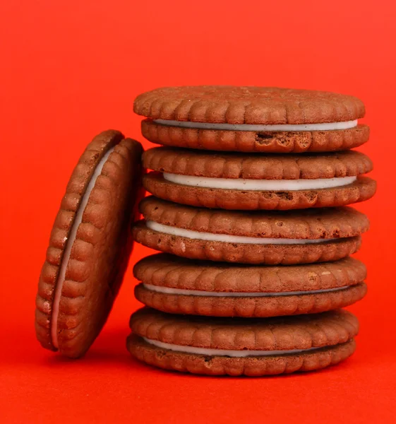 Biscoitos de chocolate com camada cremosa no fundo vermelho — Fotografia de Stock