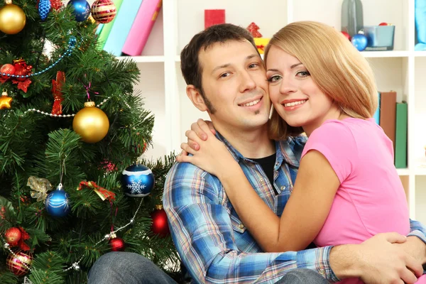 Jovem casal feliz perto de uma árvore de Natal em casa — Fotografia de Stock