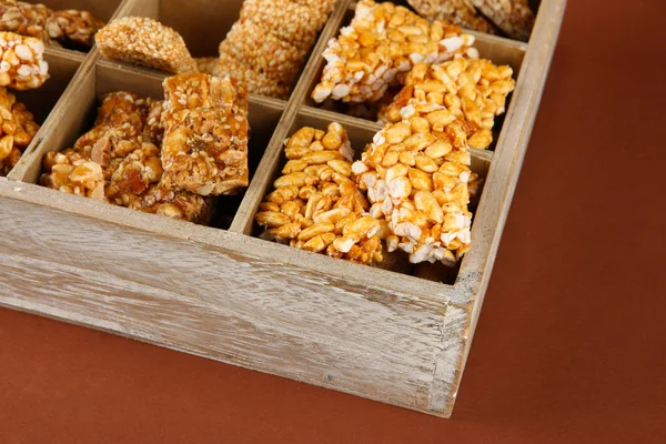 Tasty sweets (kozinaki)in wooden crate on brown background — Stock Photo, Image