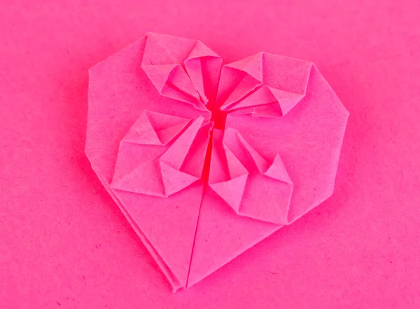 Origami corazón de papel sobre fondo rosa — Foto de Stock