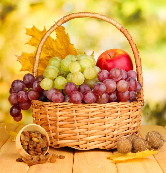 Grape in basket with nuts on wooden table — Stock Photo, Image