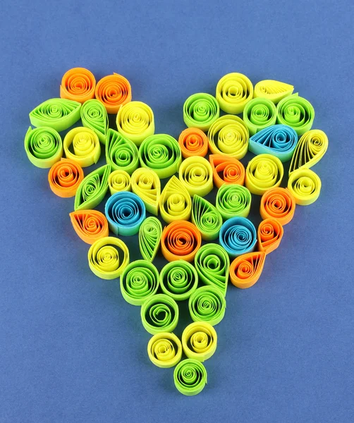 Quilling colorato disposti in forma di cuore su sfondo blu — Foto Stock