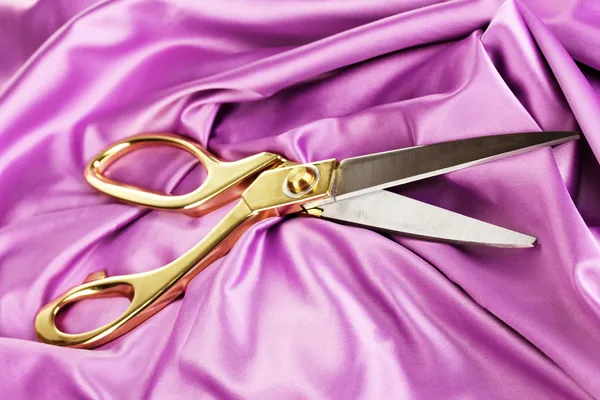 Metal scissors on purple fabric — Stock Photo, Image