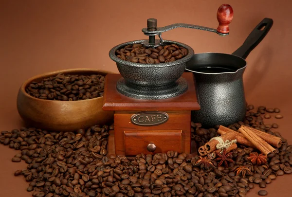 Coffee grinder, turk and coffee beans on brown background — Stock Photo, Image