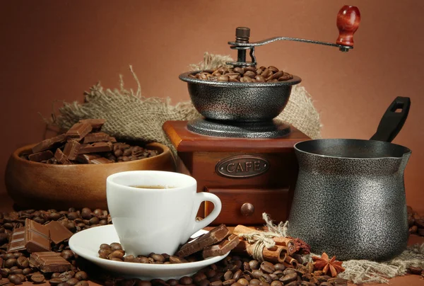 Cup of coffee, grinder, turk and coffee beans on brown background — Stock Photo, Image