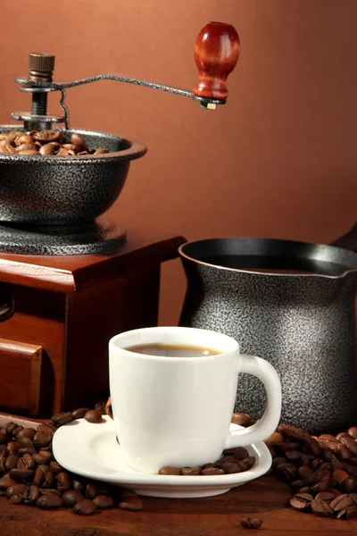 Koffiemolen, turk en kopje koffie op bruine achtergrond — Stockfoto