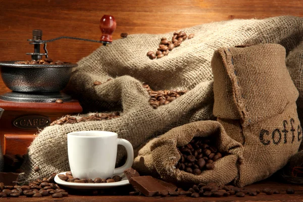 Kaffeemühle und Tasse Kaffee auf braunem Holzhintergrund — Stockfoto