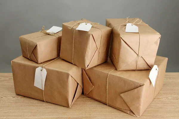 Parcels boxes with kraft paper, on wooden table on grey background — Stock Photo, Image