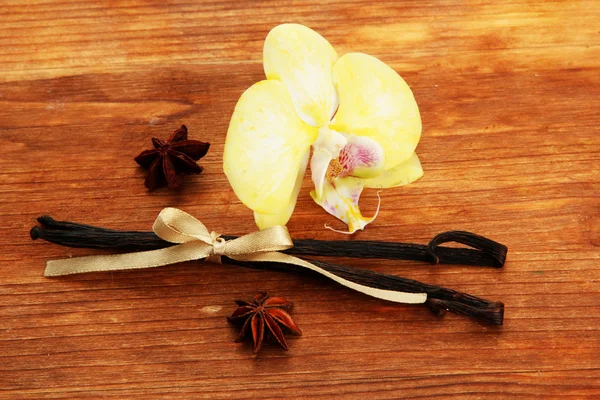 Vainas de vainilla y anís con flor, sobre fondo de madera marrón —  Fotos de Stock