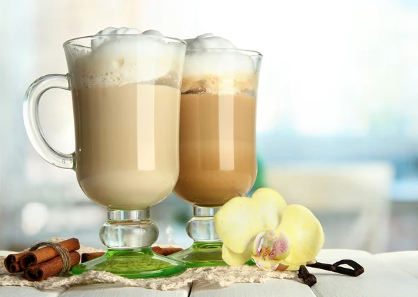 Café latte parfumé dans des tasses à verres avec des épices, sur une table en bois — Photo