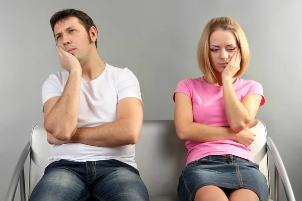 Pareja joven discutiendo sobre fondo gris — Foto de Stock