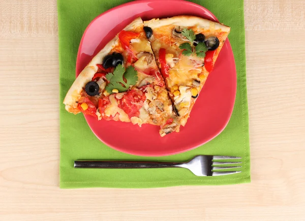 Delicious slice of pizza on color plate close-up on wooden table Royalty Free Stock Photos