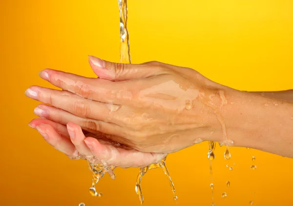 Lavar as mãos sobre fundo laranja close-up — Fotografia de Stock