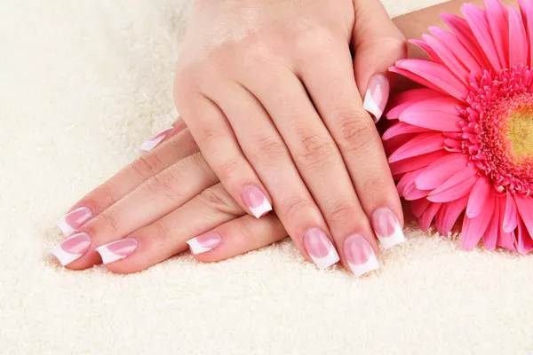 Woman hands with french manicure and flower on towel — Stock Photo, Image