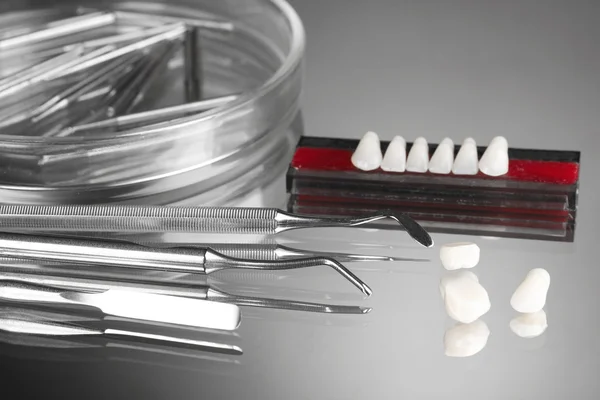 Sett med tannverktøy med tannprotese på grå bakgrunn – stockfoto