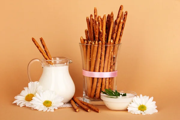 Tasty crispy sticks in glass cup on beige background — Stock Photo, Image