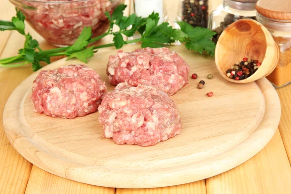 Raw meatballs with spices on wooden table — Stock Photo, Image