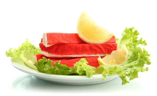 Krabbenstangen mit Salatblättern und Zitrone auf Teller isoliert auf weiß — Stockfoto