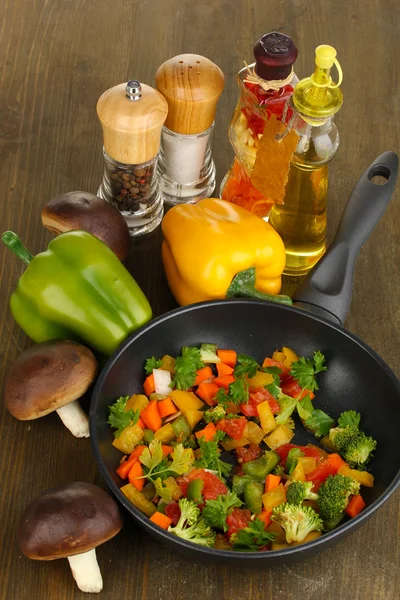 Legumes frescos fatiados em panela com especiarias e ingredientes em mesa de madeira — Fotografia de Stock