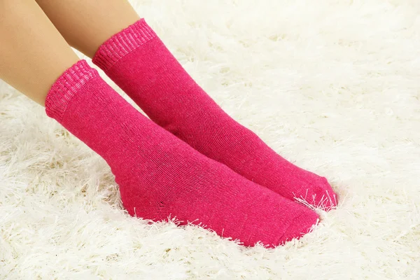 Patas femeninas en calcetines de colores sobre fondo de alfombra blanca —  Fotos de Stock