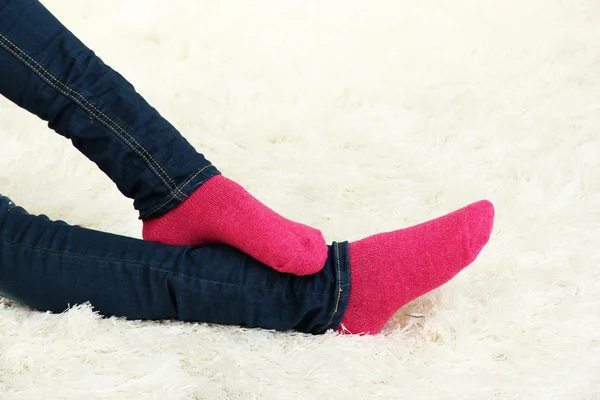 Patas femeninas en calcetines de colores sobre fondo de alfombra blanca — Foto de Stock