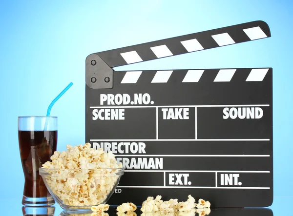 Movie clapperboard, cola and popcorn on blue background — Stock Photo, Image