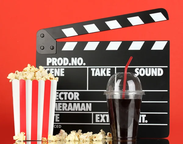 Filmklappbrett, Cola und Popcorn auf rotem Hintergrund — Stockfoto