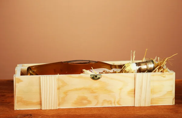 Botella de vino en caja de madera sobre mesa de madera sobre fondo marrón — Foto de Stock