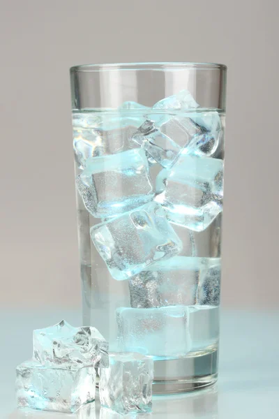 Cubos de gelo em vidro sobre fundo azul claro — Fotografia de Stock