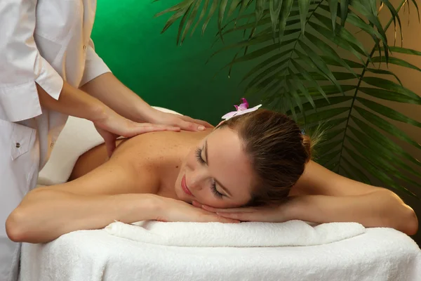 Hermosa joven en el salón de spa recibiendo masaje, sobre fondo verde —  Fotos de Stock