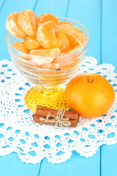 Смачні скибочки мандарину в скляній мисці на синьому фоні — стокове фото