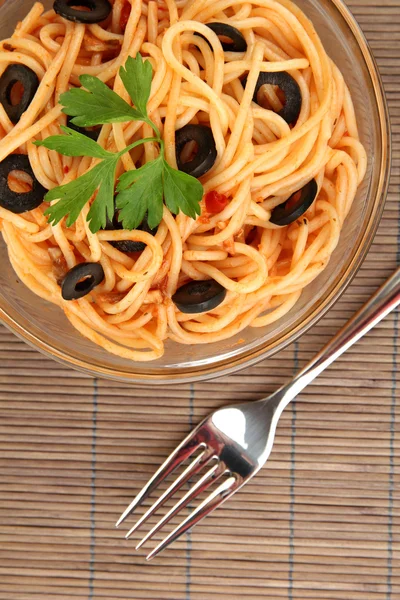Espaguetis italianos en tazón de vidrio en la estera de bambú de cerca — Foto de Stock
