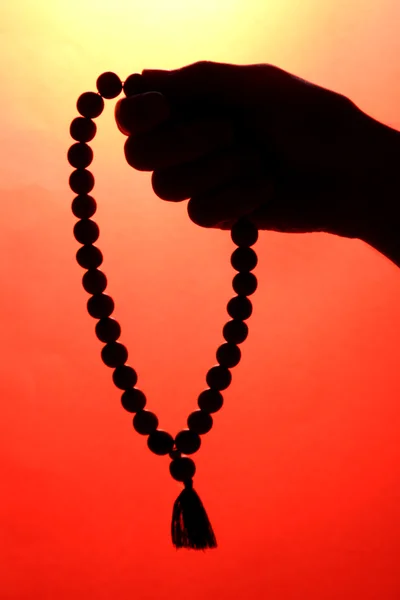 Mano masculina con rosario, sobre fondo rojo — Foto de Stock