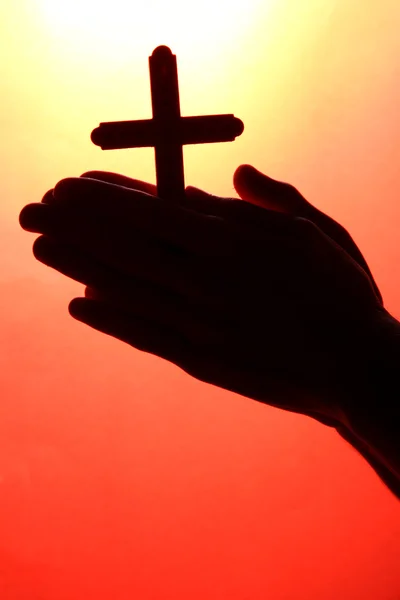 Hombre manos con crucifijo, sobre fondo rojo — Foto de Stock