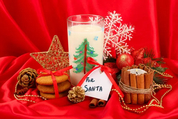 Cookies voor santa: Conceptuele afbeelding van gember koekjes, melk en kerst decoratie op rode achtergrond — Stockfoto